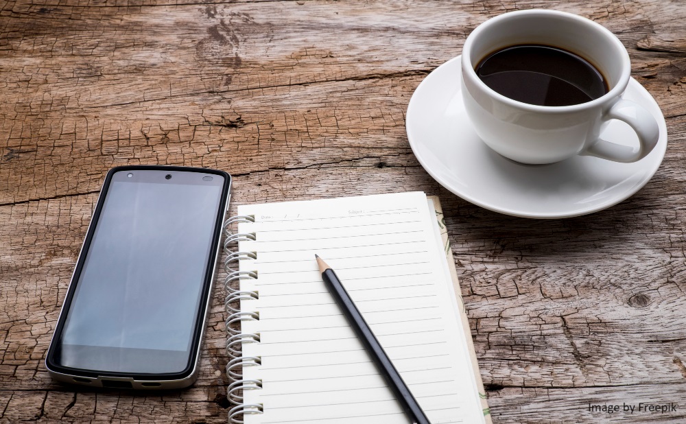 Image of a cell phone on a table in a coffee shop.