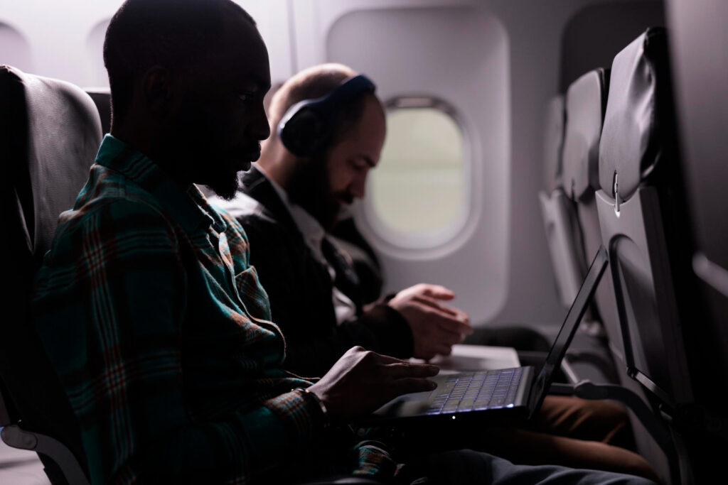 image of two people on a plane using computers
