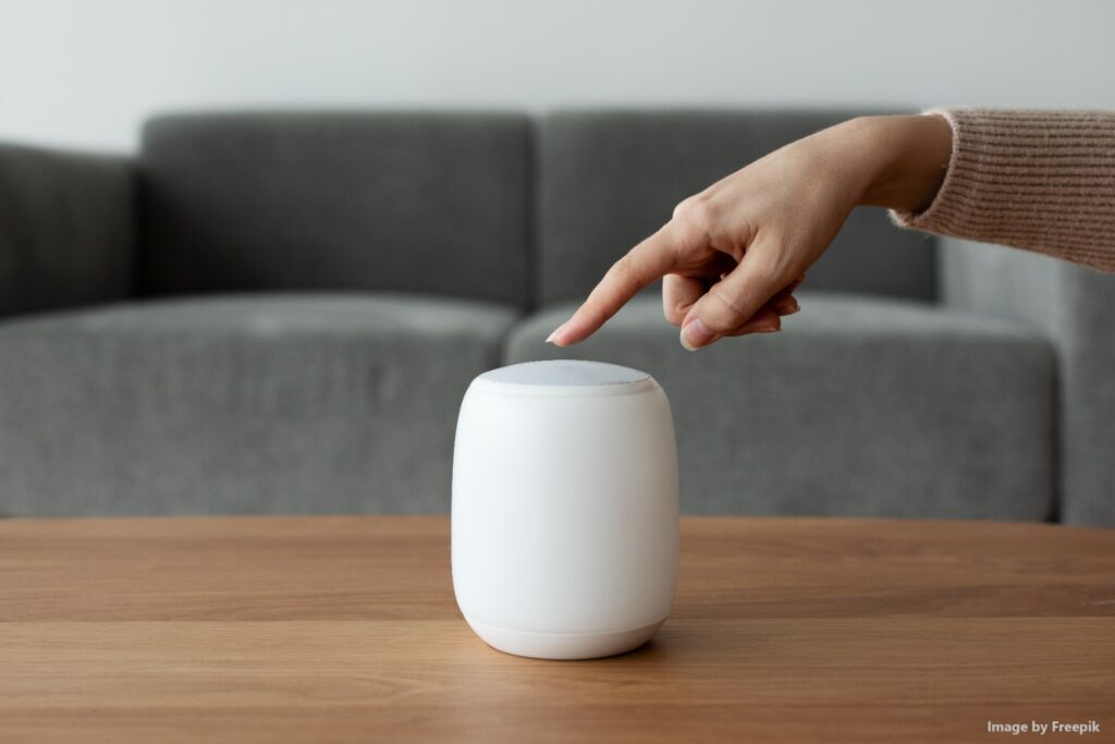 Image of someone pressing the mute button on a smart speaker