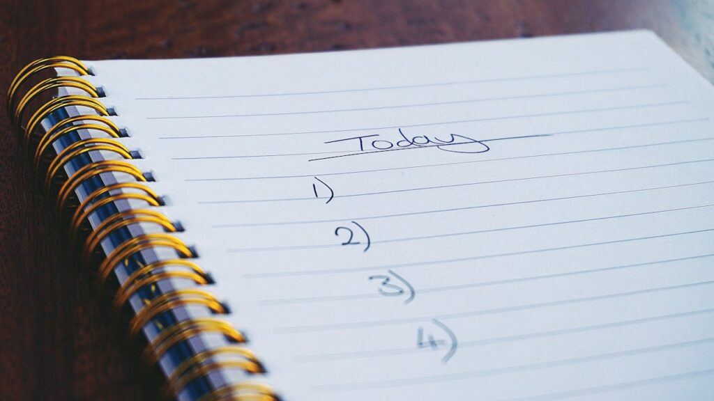 Close-up of an open spiral notebook with a handwritten to-do list titled 'Today' and numbered tasks left blank—symbolizing the importance of including digital safety checks on your daily agenda, especially during tax season when AI-generated scams are on the rise.